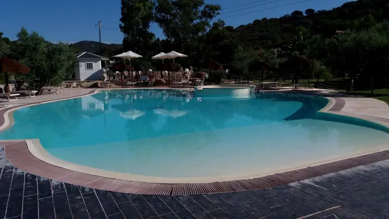 Une piscine rectangulaire bordée d'une terrasse ensoleillée.