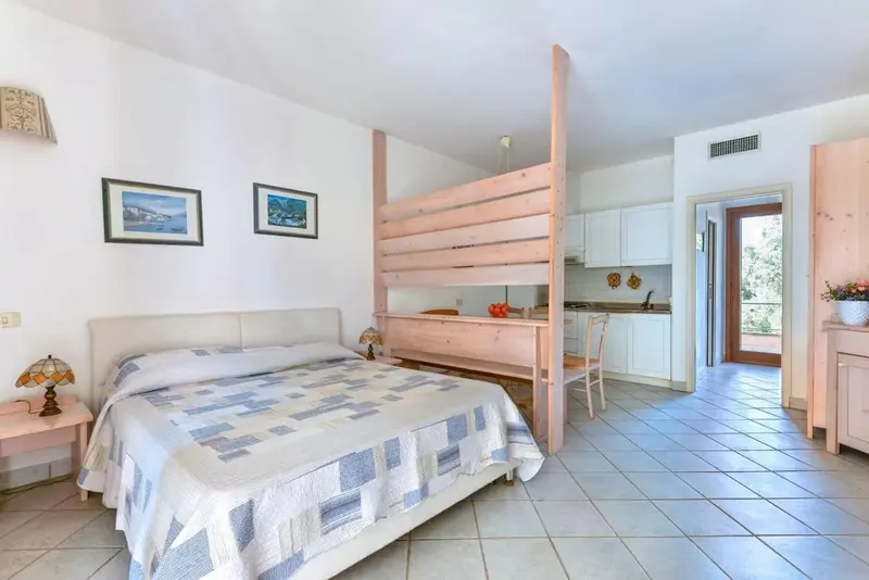 Une chambre lumineuse avec un lit et un coin cuisine.