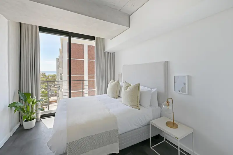 Une chambre lumineuse avec un grand lit et une vue sur la ville.