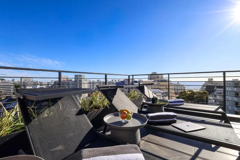 Terrasse aménagée avec chaises longues et vue sur la ville.