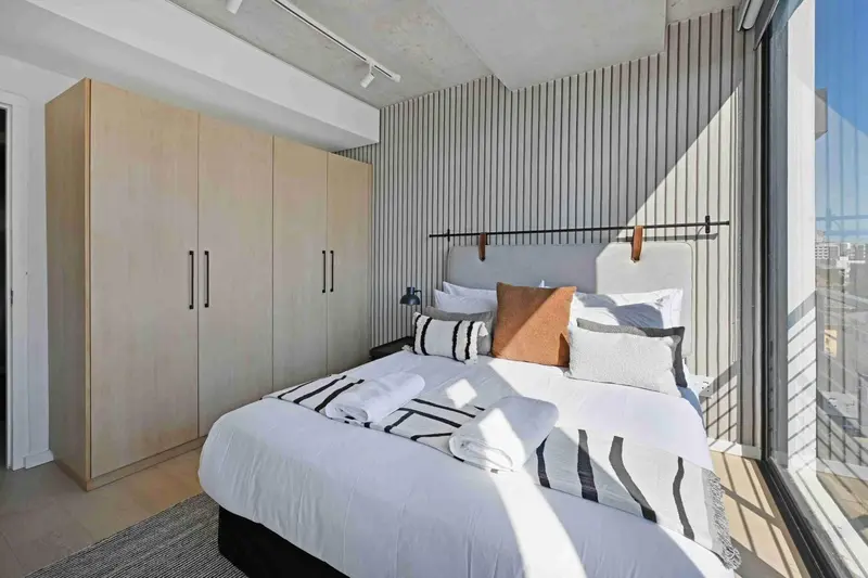 Une chambre lumineuse avec un grand lit et des rangements.