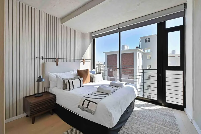 Une chambre lumineuse avec un grand lit et une vue sur la ville.