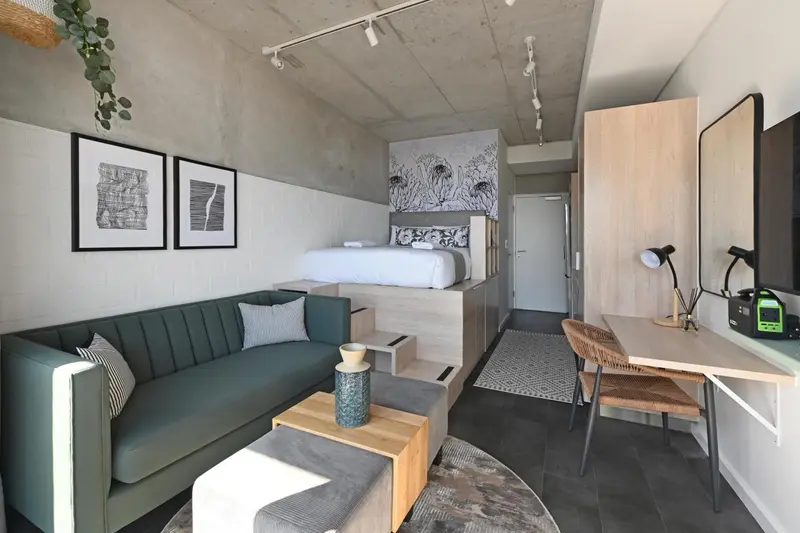 Une chambre moderne avec un canapé vert et un lit surélevé.