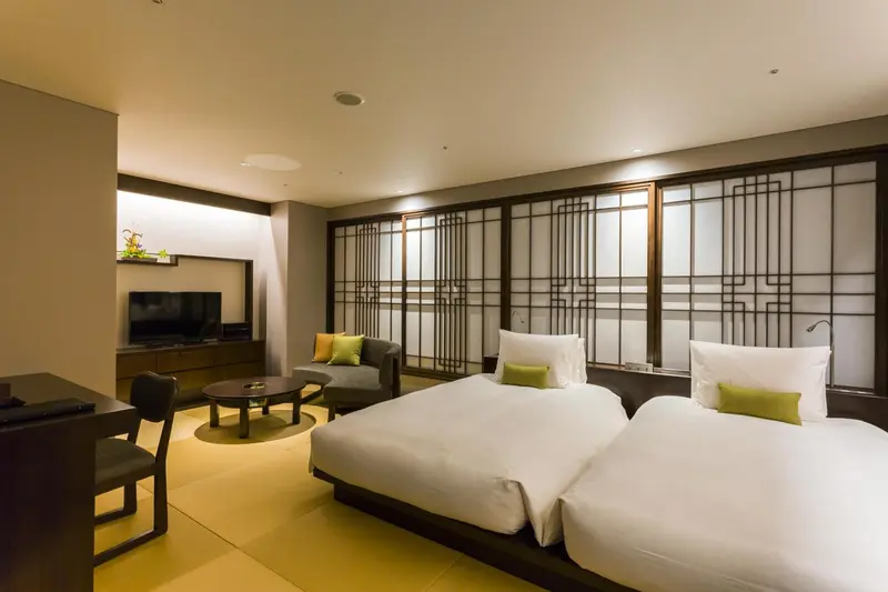 Une chambre lumineuse avec deux lits simples et un coin salon.
