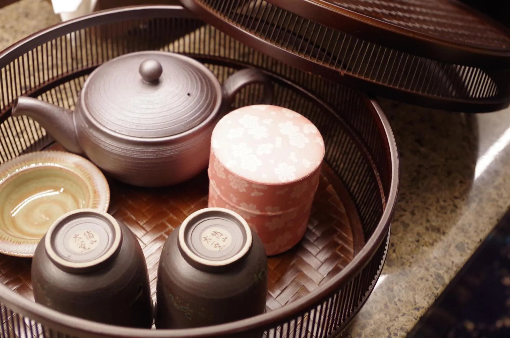 Une nature morte avec une théière et des tasses en céramique sur un plateau en bambou.