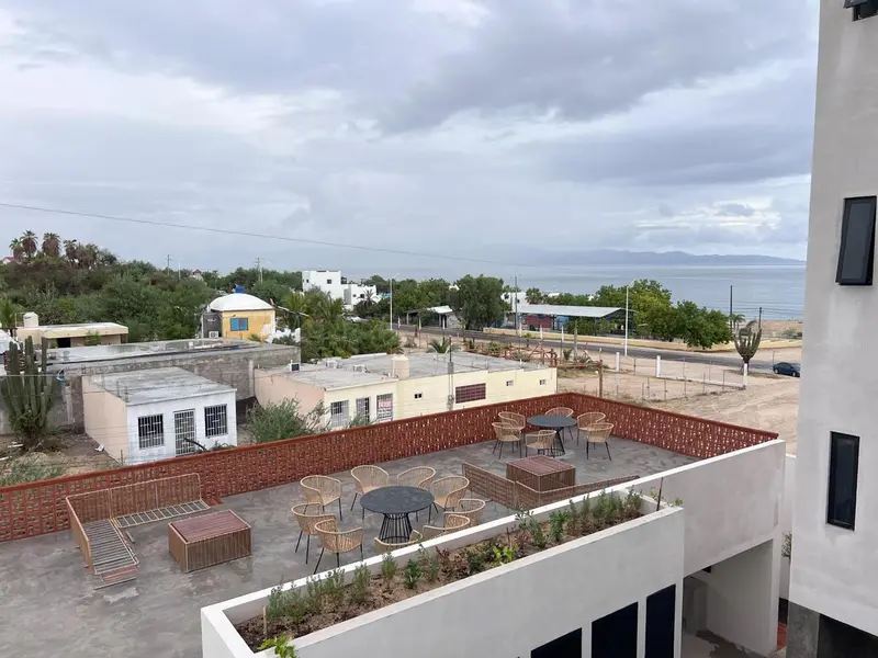 Terrasse aménagée avec tables et chaises donnant sur un paysage côtier.