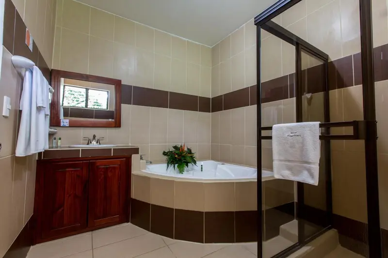 Une salle de bain lumineuse avec baignoire d'angle et douche à l'italienne.