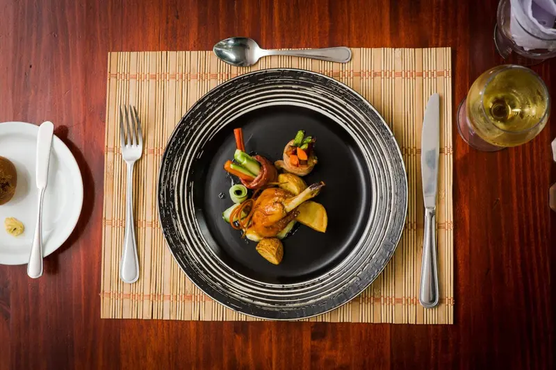 Une assiette décorative présente un plat raffiné avec des légumes et de la viande.
