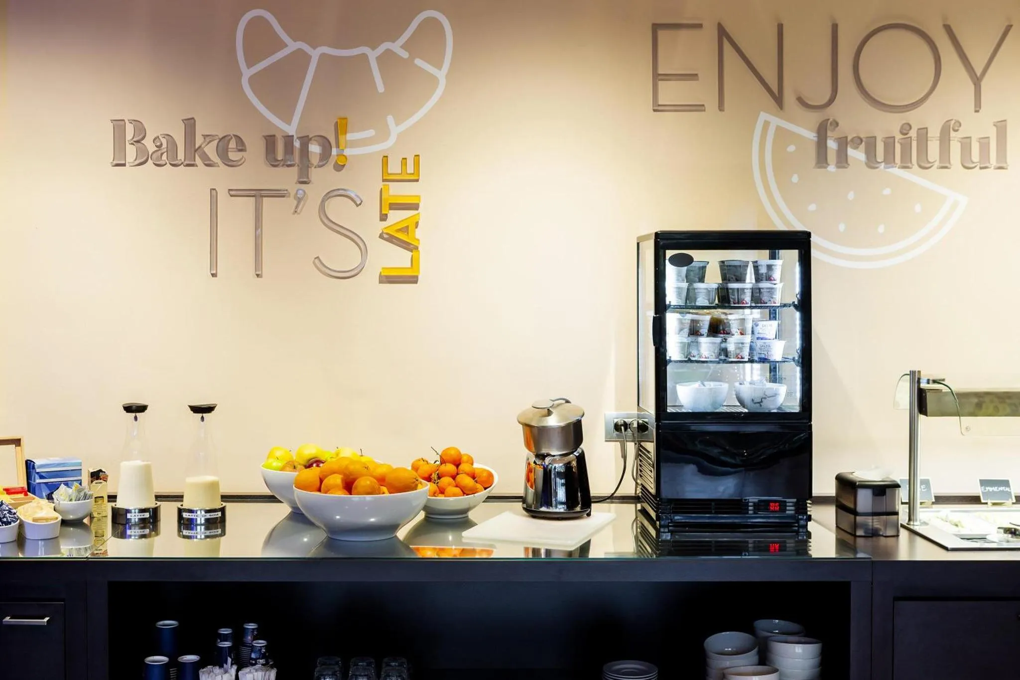 Un comptoir de petit-déjeuner présente des boissons, des fruits et une machine à café.