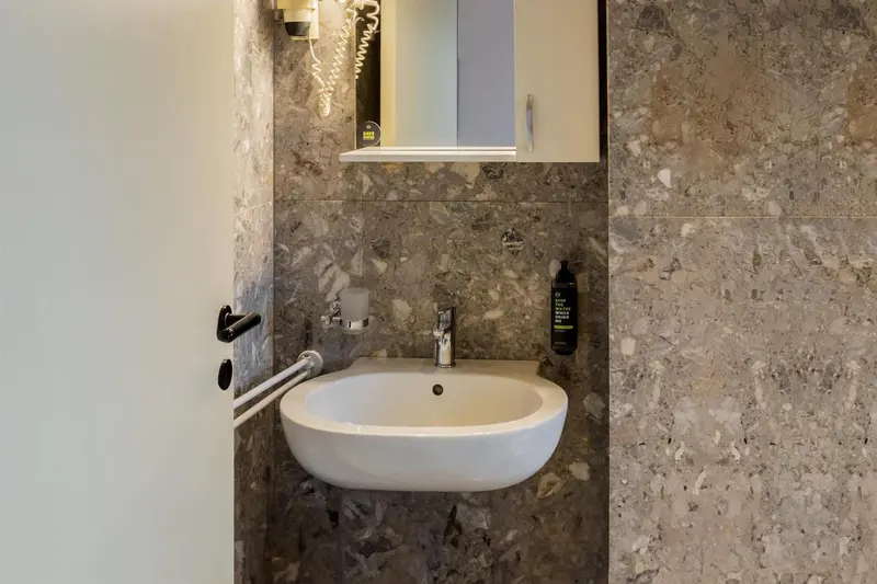 Lavabo blanc et robinetterie chromée dans une salle de bain carrelée.