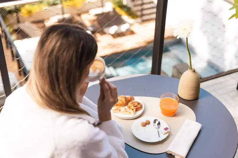 Une personne prend son petit-déjeuner à une table en extérieur.