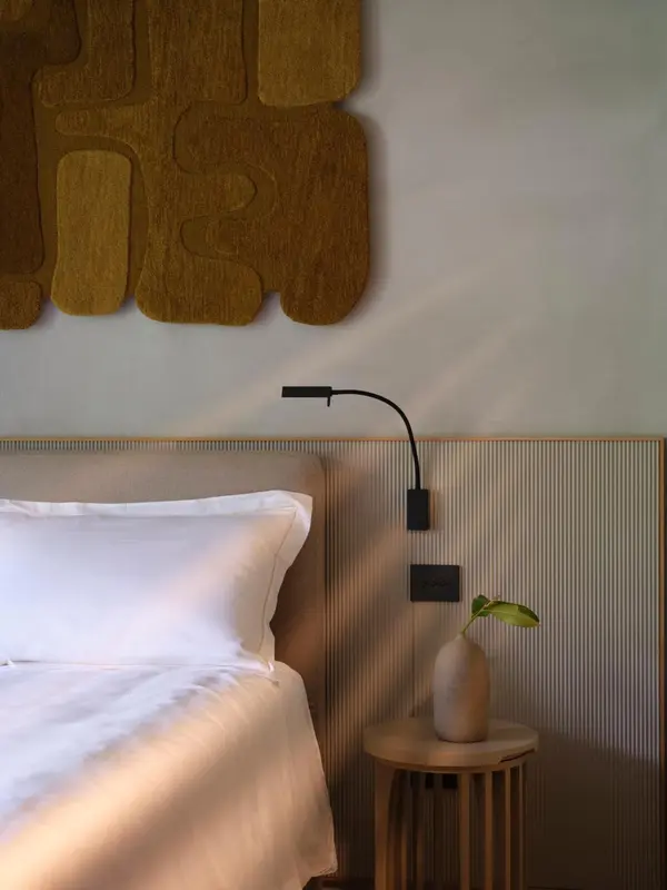 Une chambre lumineuse avec un lit fait et une décoration murale abstraite.