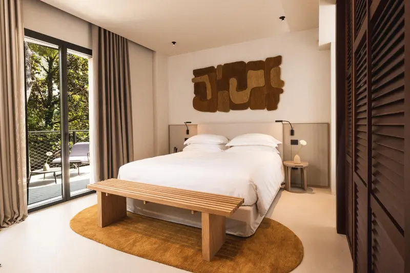 Une chambre lumineuse avec un grand lit et une décoration murale abstraite.