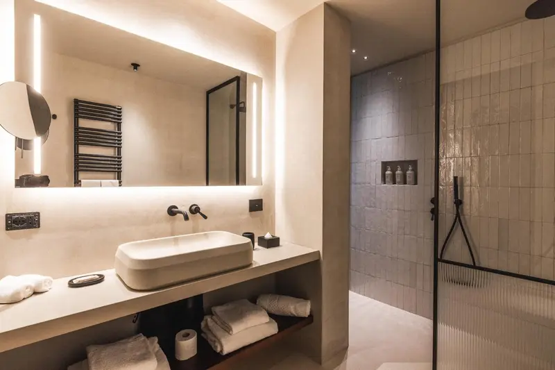 Une salle de bain moderne avec douche à l'italienne et vasque lumineuse.