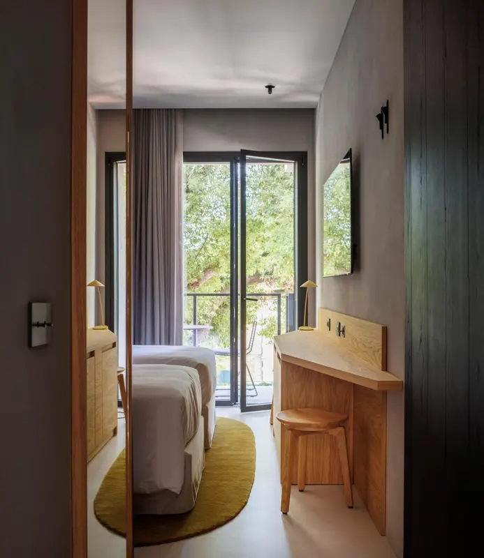 Une chambre lumineuse avec un lit double et un coin bureau donnant sur une vue verdoyante.