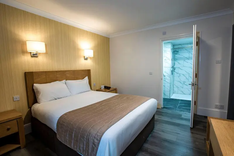 Une chambre lumineuse avec un lit double et une salle de bain attenante.