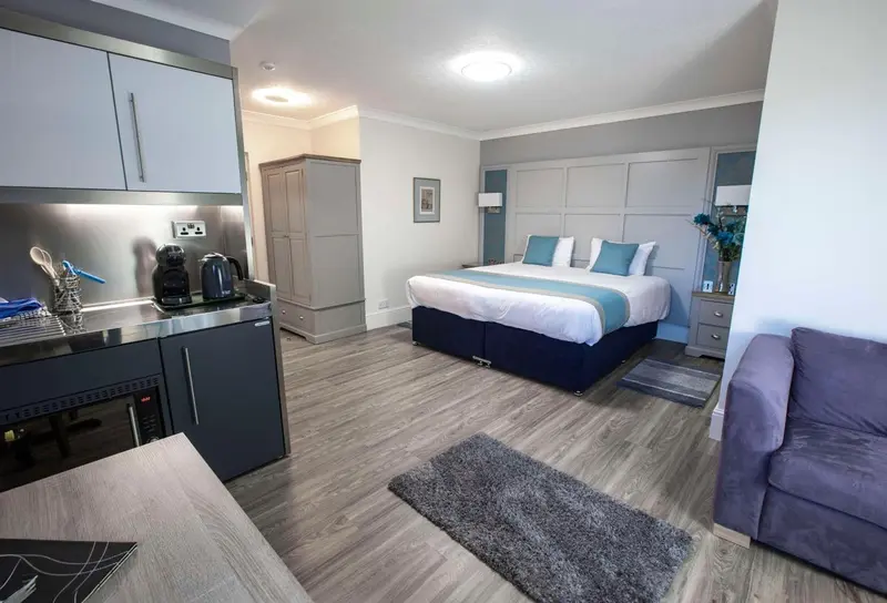 Une chambre moderne avec un espace cuisine et un lit fait.