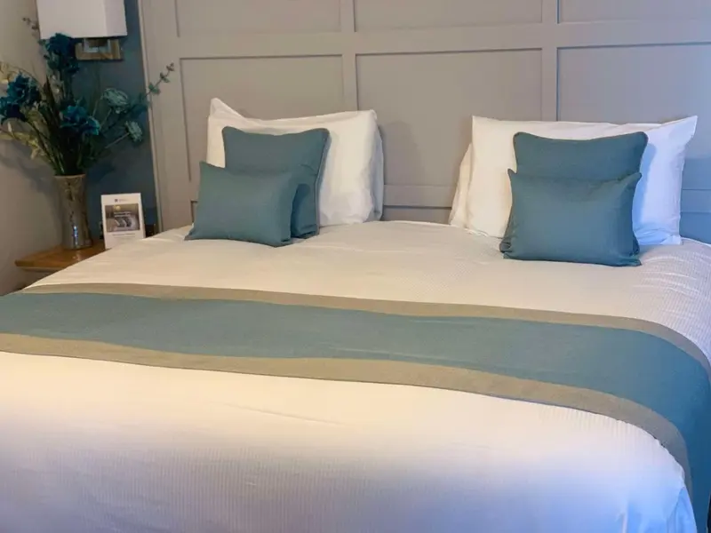 Un lit double est soigneusement fait avec des oreillers et des coussins.