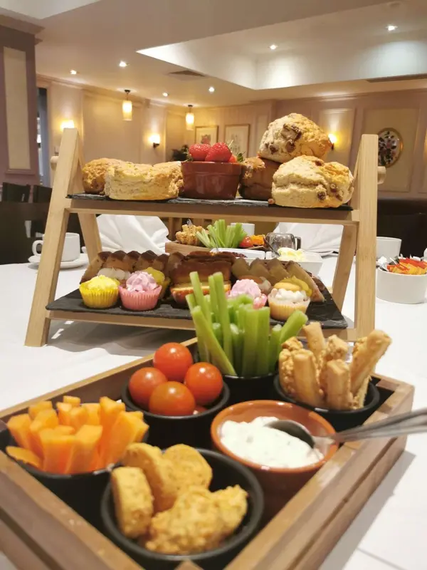 Présentation de pâtisseries, de fruits et de crudités sur une table nappée.