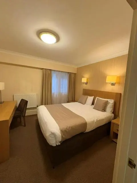 Une chambre d'hôtel avec un lit double et un bureau.