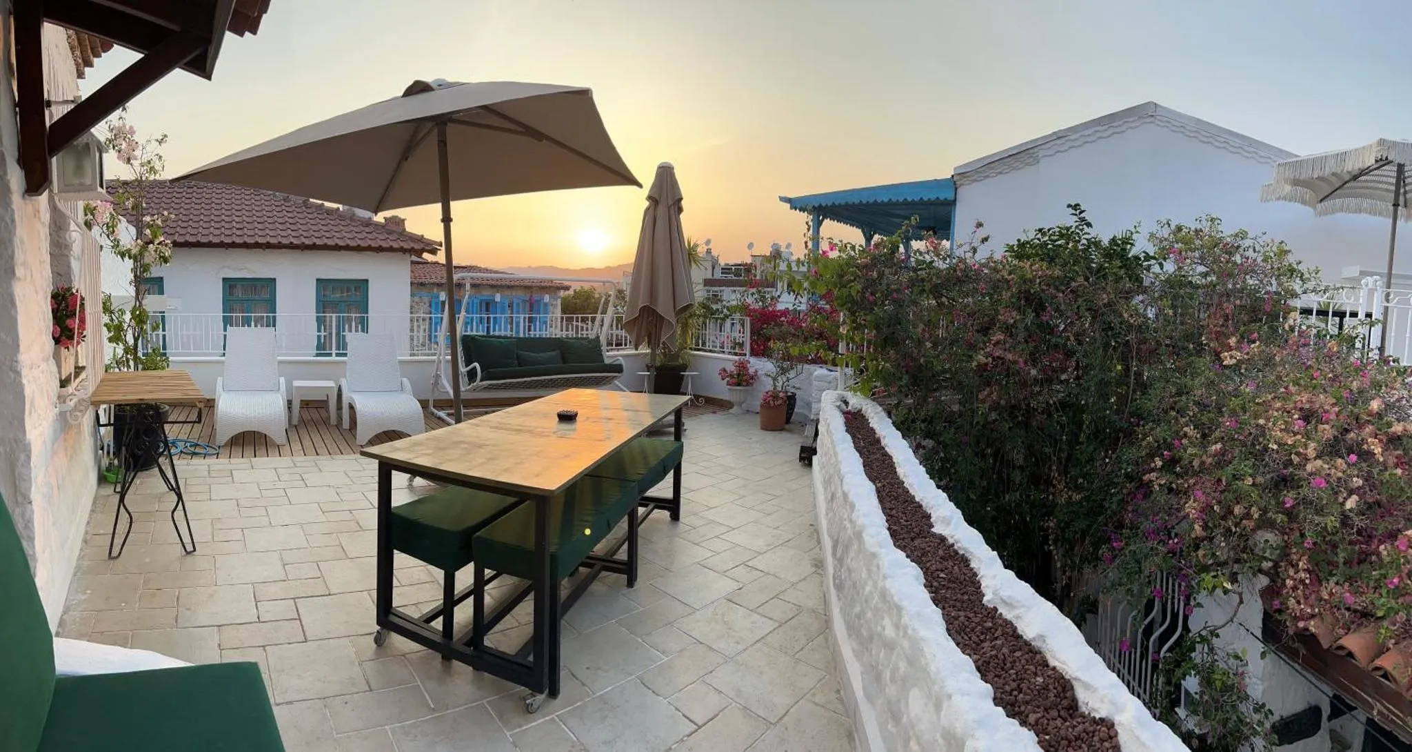 Terrasse aménagée avec mobilier de jardin et vue sur un coucher de soleil.