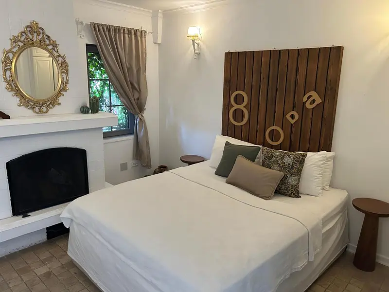 Une chambre lumineuse avec un lit double et une cheminée.