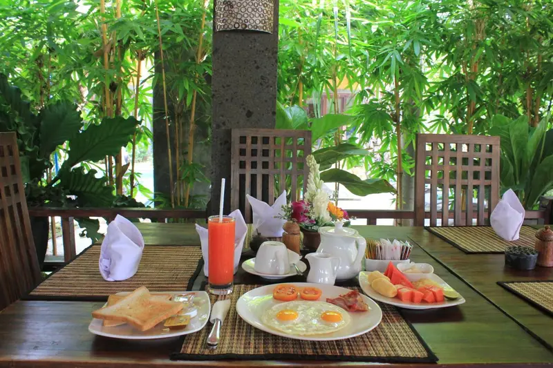 Une table est dressée pour le petit-déjeuner avec des viennoiseries, des fruits et des boissons.