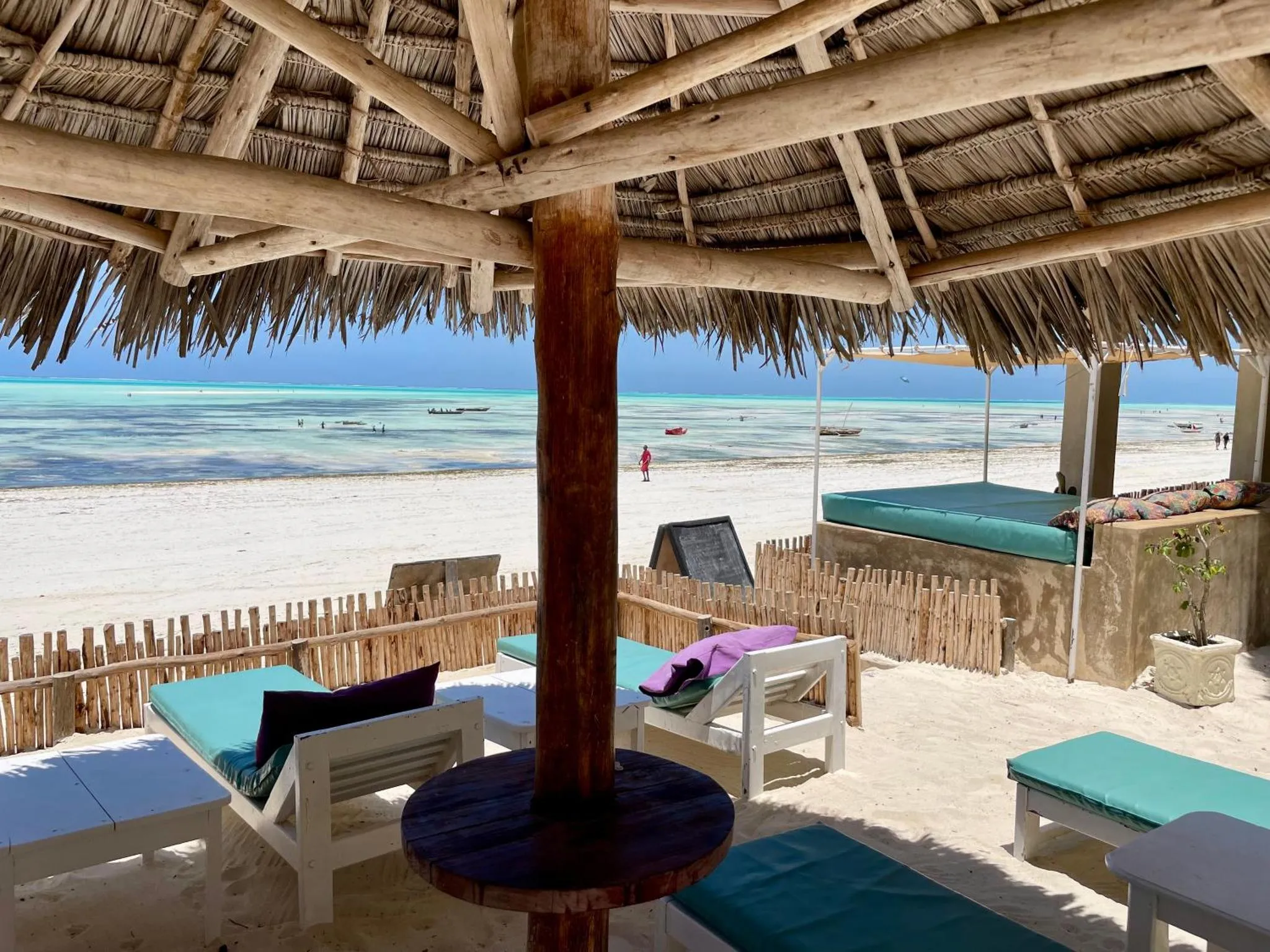 Espace de détente ombragé avec vue sur une plage de sable blanc et une mer turquoise.