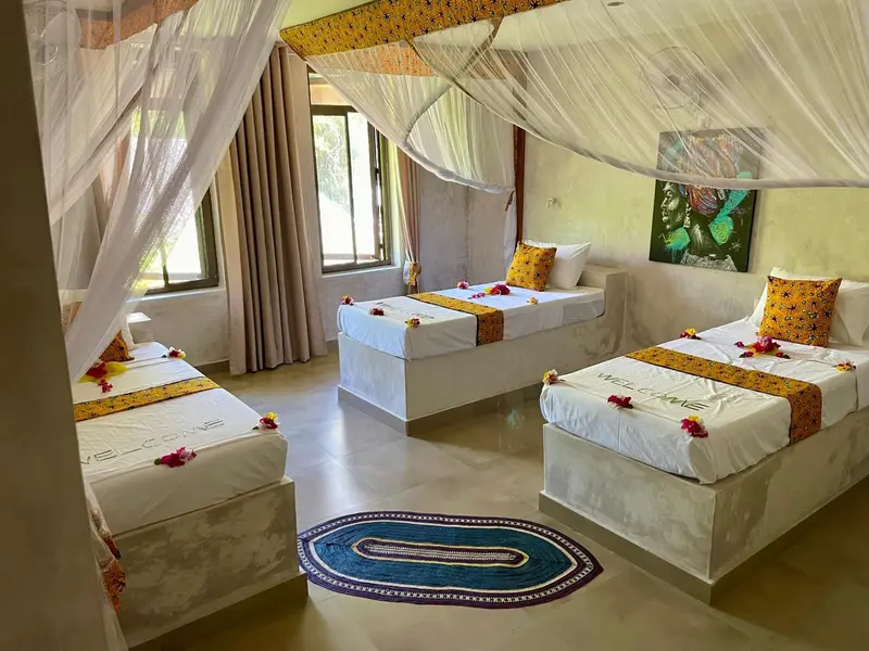 Trois lits simples décorés de fleurs dans une chambre lumineuse.