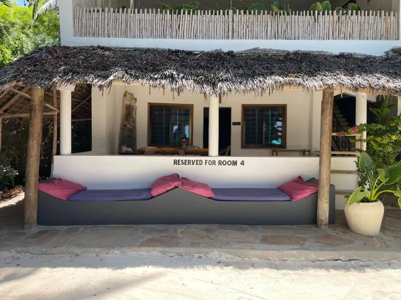 Terrasse ombragée avec assises et végétation tropicale.