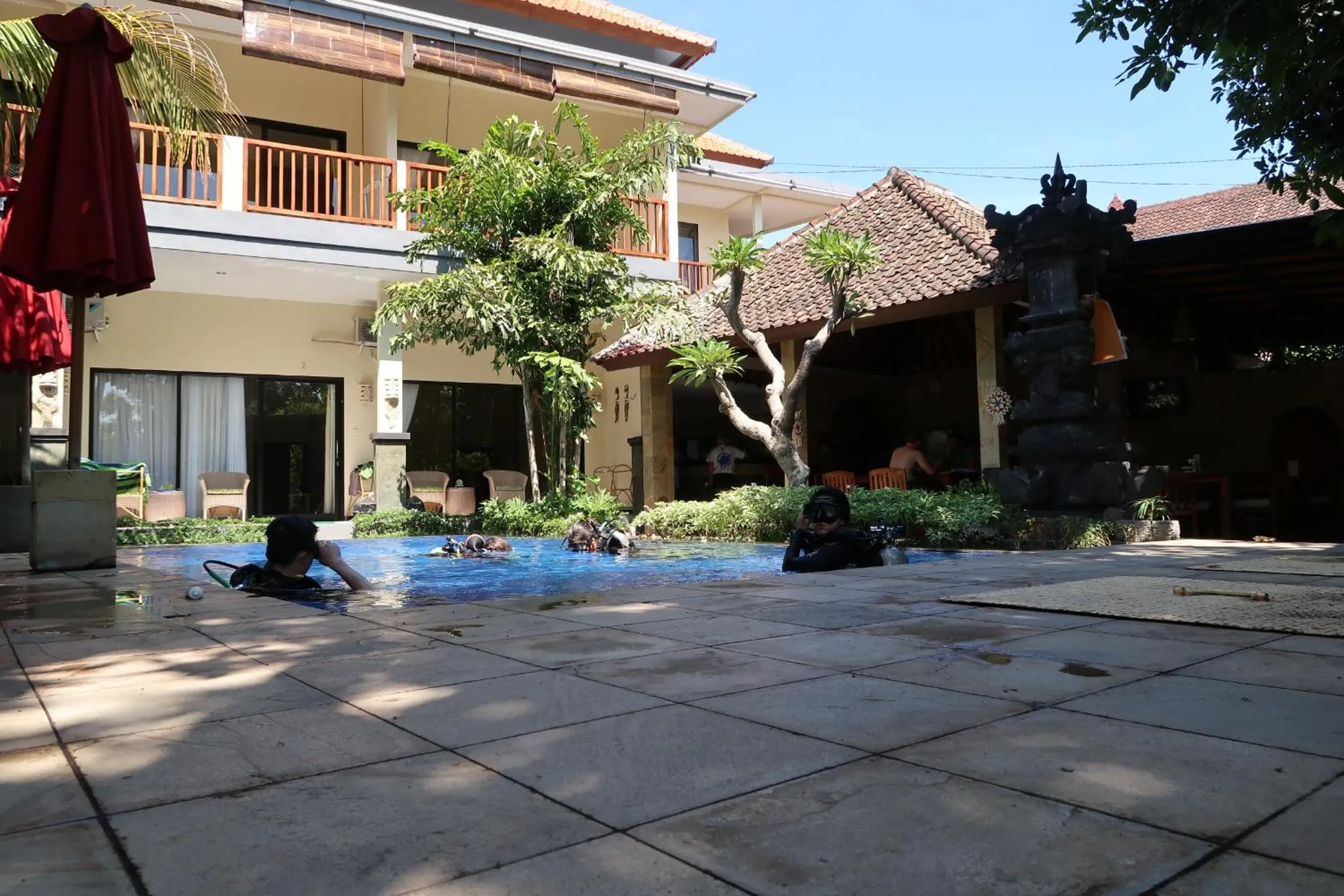 Une piscine rectangulaire bordée d'une terrasse carrelée, avec des personnes se baignant.