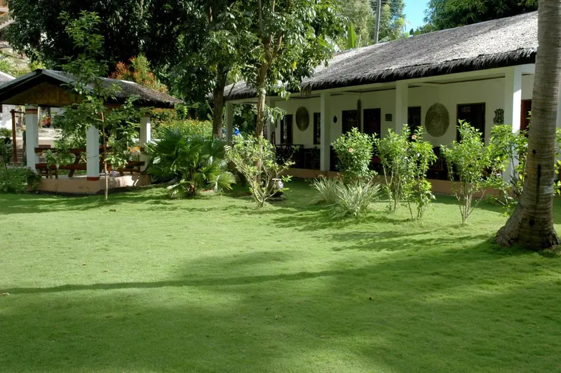 Bâtiment blanc à colonnes entouré d'une pelouse verdoyante et de végétation tropicale.