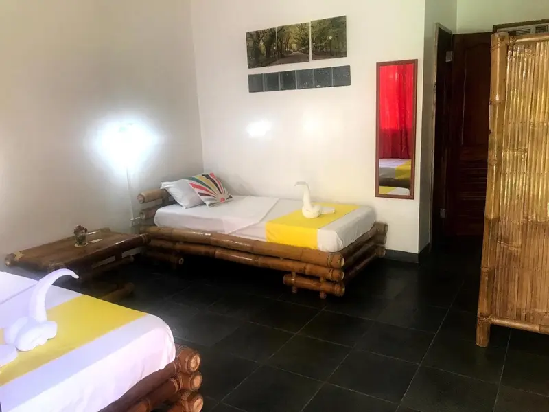 Une chambre lumineuse avec deux lits simples en bambou et une décoration murale colorée.