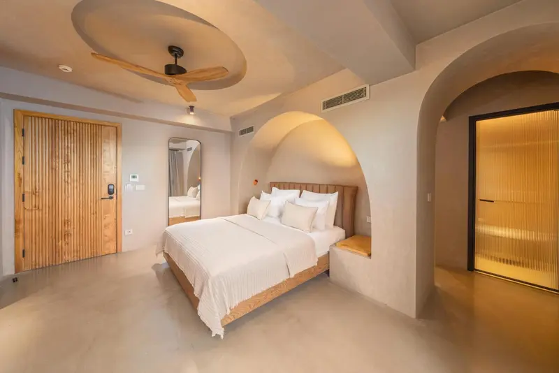 Une chambre lumineuse avec un grand lit et des arches décoratives.