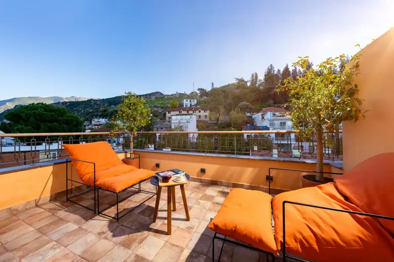 Terrasse ensoleillée avec mobilier d'extérieur et vue sur la ville.