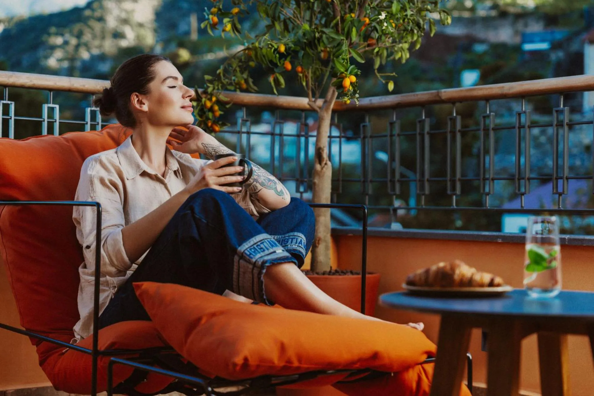 Une femme se détend sur une terrasse avec une boisson chaude.