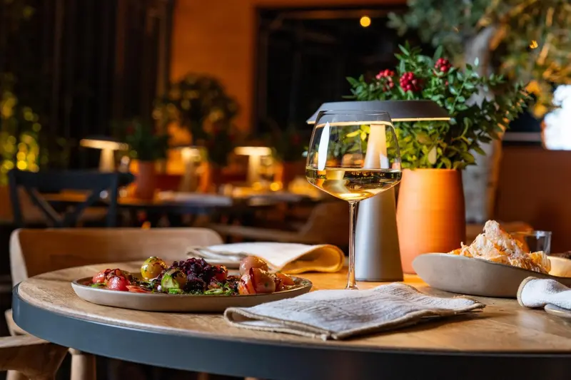 Une table est dressée avec un plat de salade et un verre de vin.