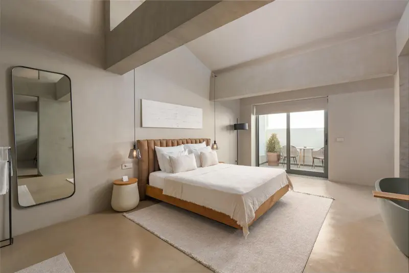 Une chambre lumineuse avec un grand lit et un accès à une terrasse.