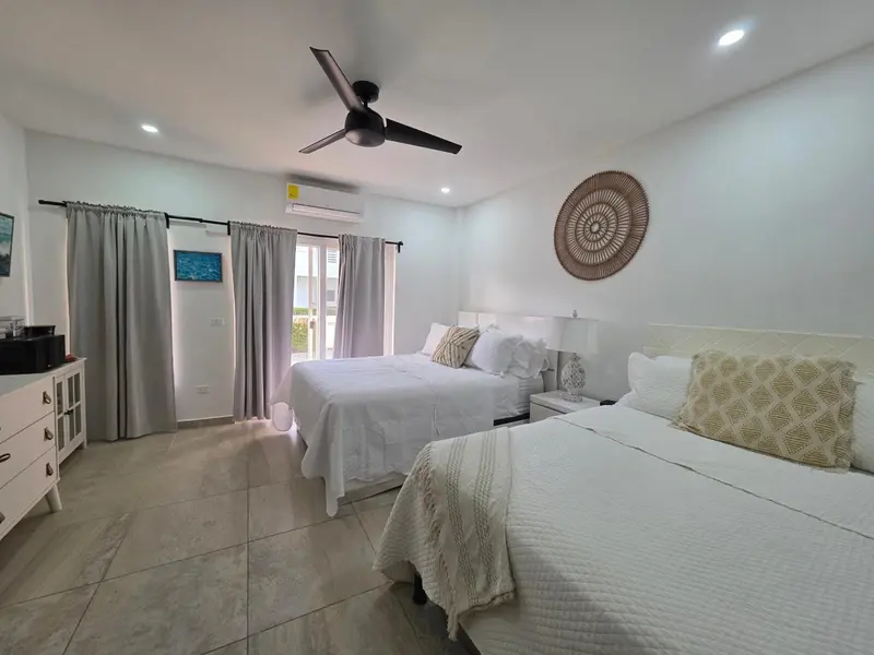 Une chambre lumineuse avec deux lits doubles et une décoration sobre.