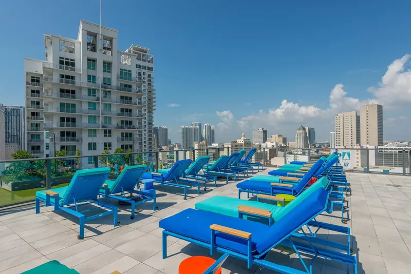 Transats bleus alignés sur une terrasse ensoleillée avec vue sur la ville.