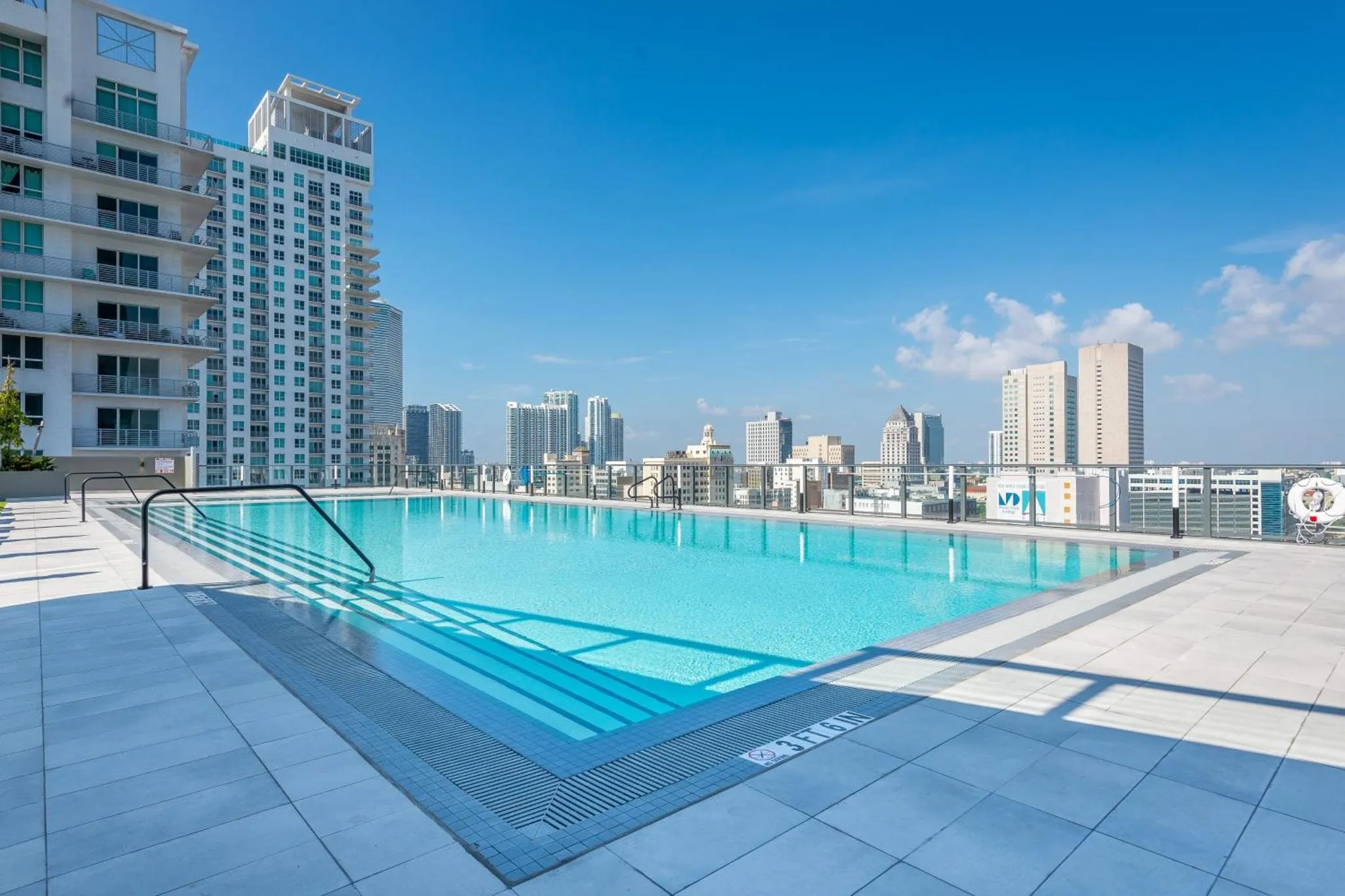 Piscine rectangulaire sur un toit-terrasse avec vue sur la ville.