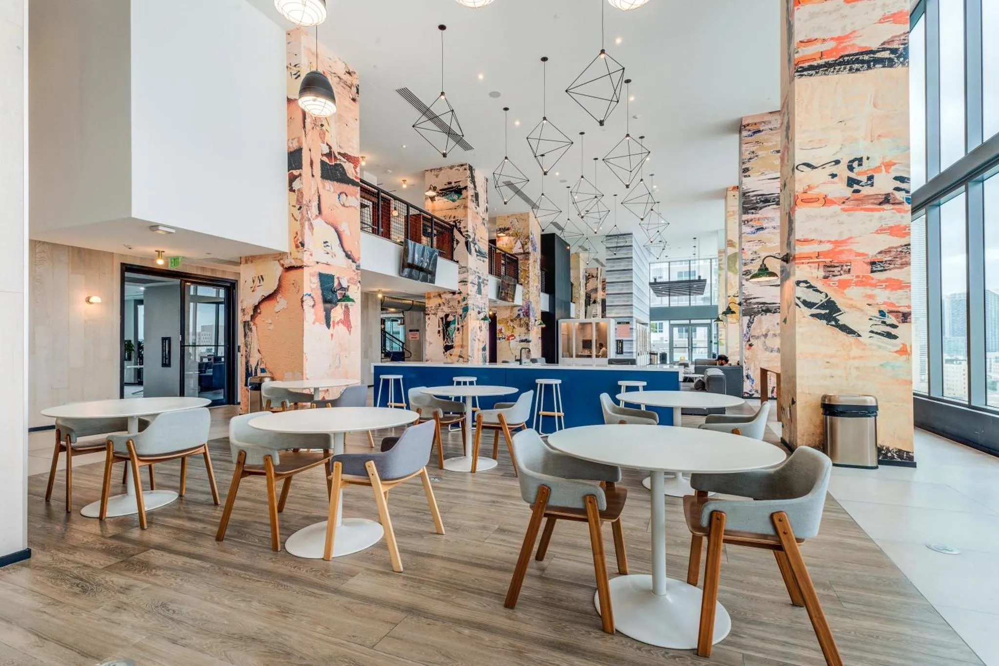 Une salle lumineuse avec des tables et des chaises près d'une grande fenêtre.