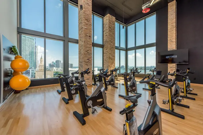 Une salle de sport lumineuse avec des vélos d'exercice face à une grande baie vitrée.