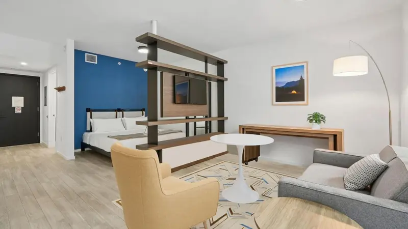 Une chambre lumineuse avec un espace salon et un bureau.