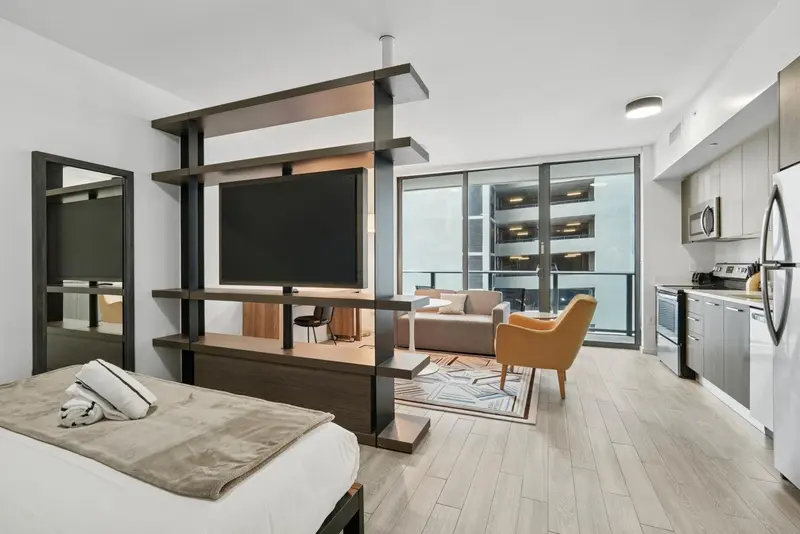 Espace de vie lumineux avec un lit, un canapé et une kitchenette.