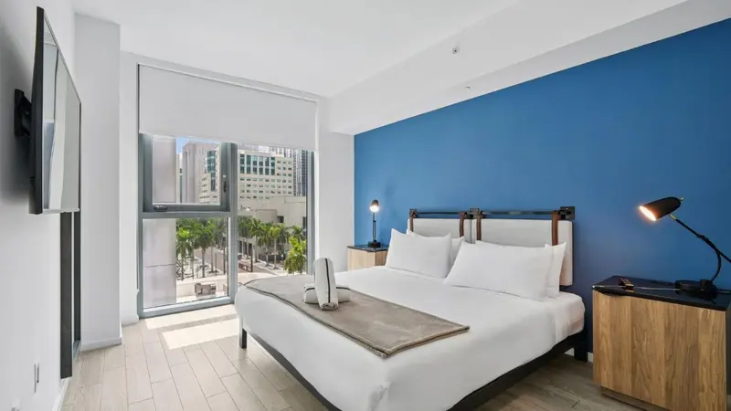 Une chambre lumineuse avec un grand lit et une vue sur la ville.