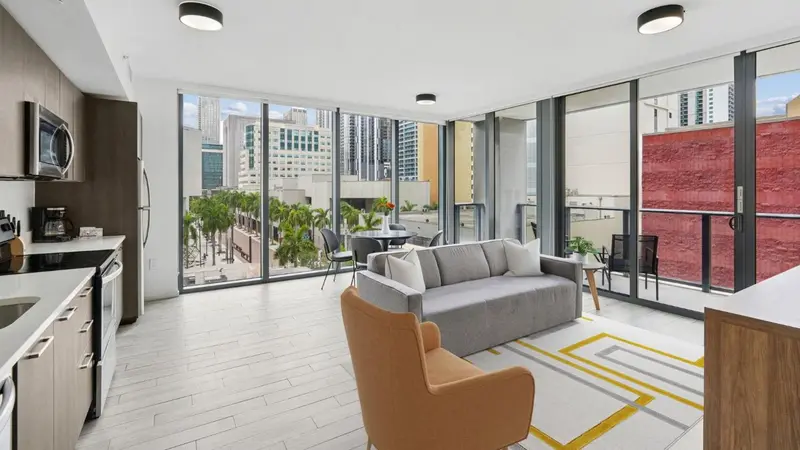Espace de vie lumineux avec cuisine équipée et vue sur la ville.