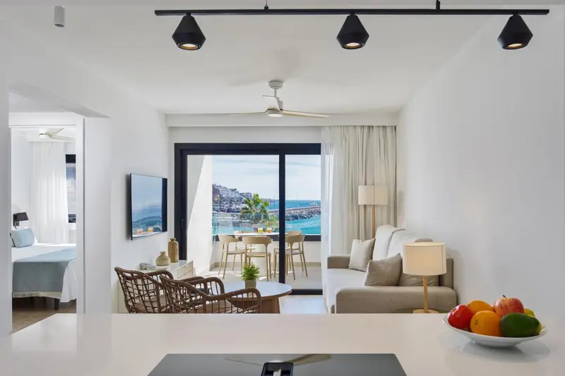 Espace de vie lumineux avec canapé, table basse et vue sur la mer.
