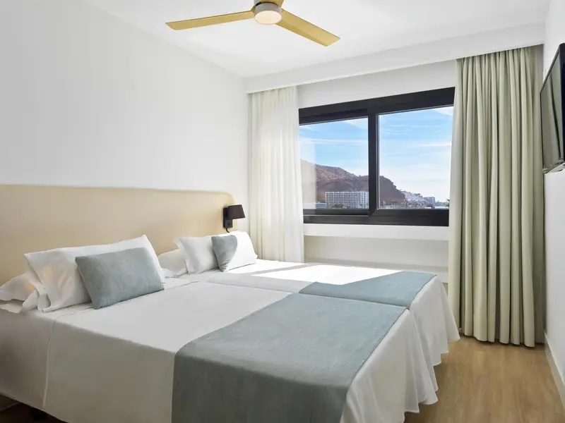 Une chambre lumineuse avec un grand lit et une vue sur un paysage montagneux.