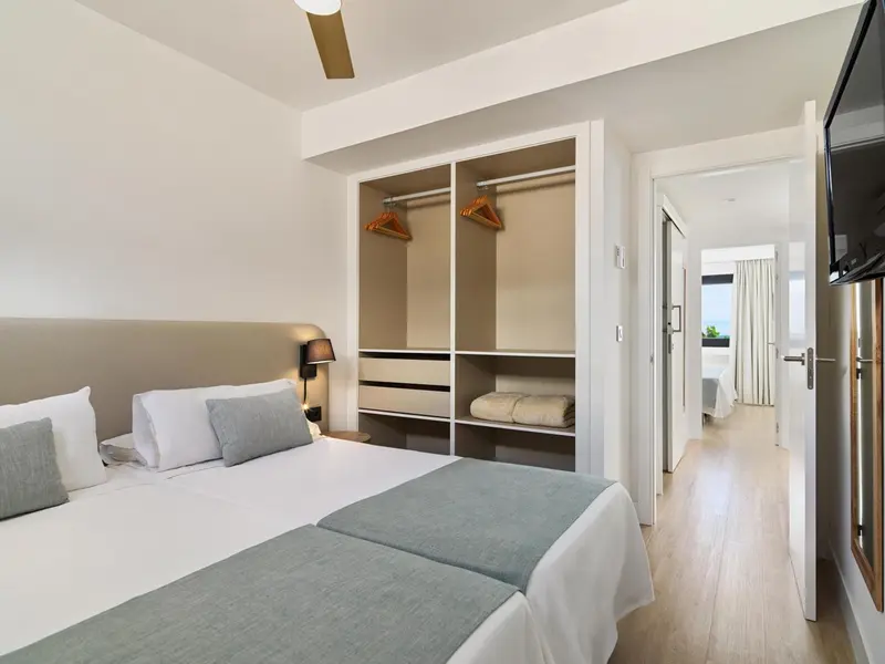 Une chambre lumineuse avec un grand lit et un placard intégré.